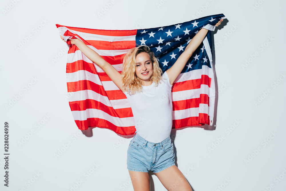 Fototapeta premium American blonde woman holding the USA flag isolated over a white background