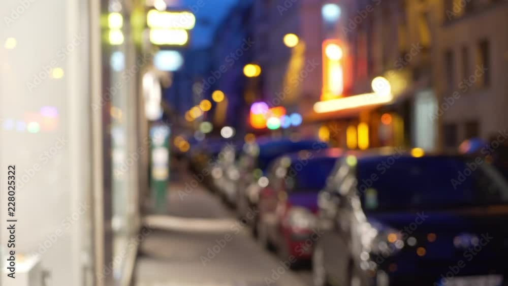 Out of focus background of cars parallel parked on city street next to shops Out of focus background of cars parallel parked on city street next to shops