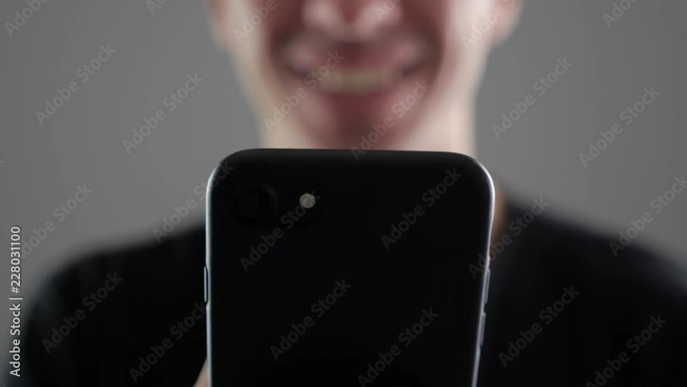 Closeup of Young Smiling Man Using Smartphone, Browsing in Internet or Checking Social Networks on white background