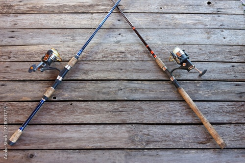 two crossed fishing rods on wooden background photo