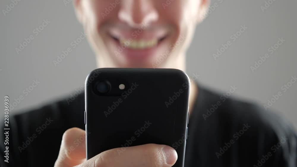 Closeup of Smiling Young Man Using Smartphone, Browsing in Internet or Checking Social Networks on white background
