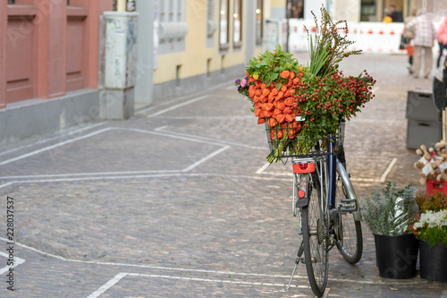 A bicycle basket filled with flowers and foliage at a European farmers market