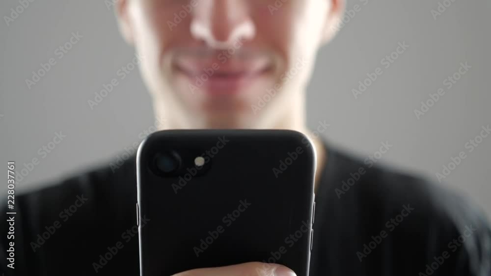 Closeup of Smiling Young Man Using Smartphone, Browsing in Internet or Checking Social Networks on white background