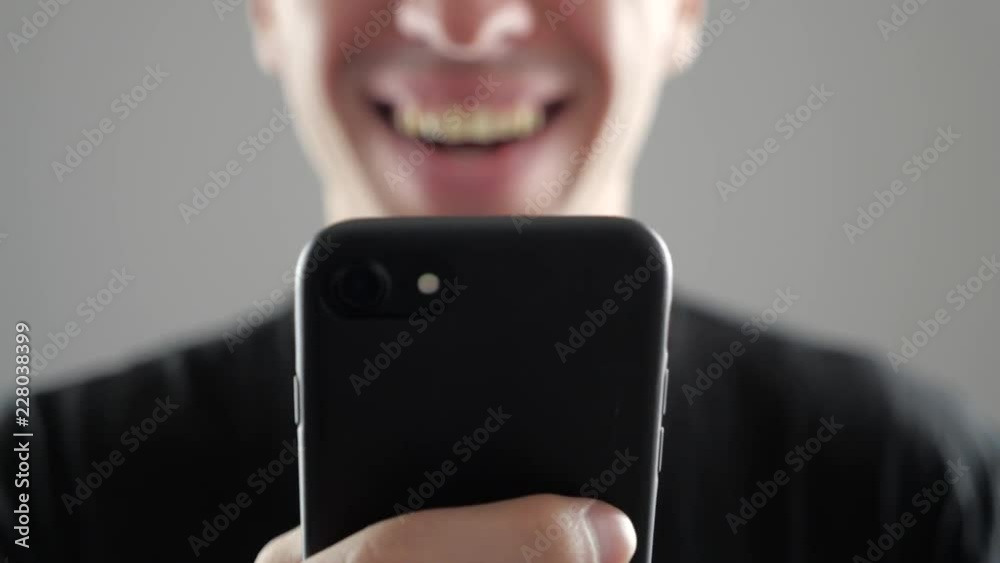 Closeup of Smiling Young Man Using Smartphone, Browsing in Internet or Checking Social Networks on white background
