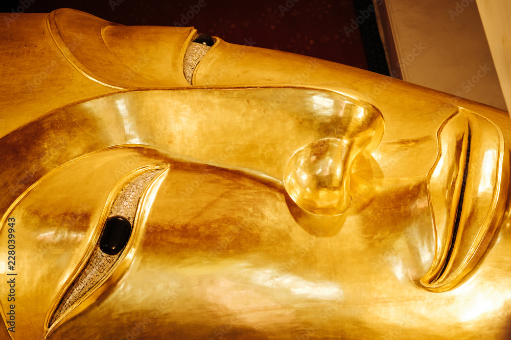 Close up image on face of old golden reclining buddha at Wat Phra Non Chakkrasi Worawihan, Singburi Province, Thailand
