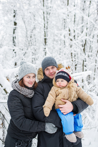 Happy family of three against the background of snow-covered trees.