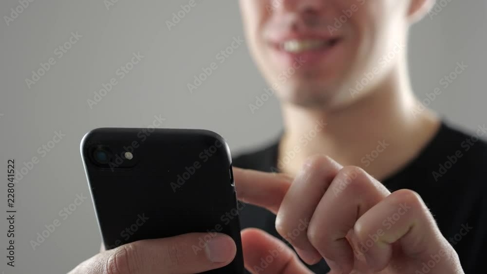 Closeup of Smiling Young Man Using Smartphone, Browsing in Internet or Checking Social Networks on white background