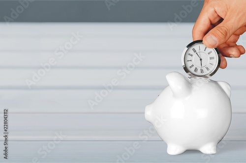 Hand depositing clock in piggy bank