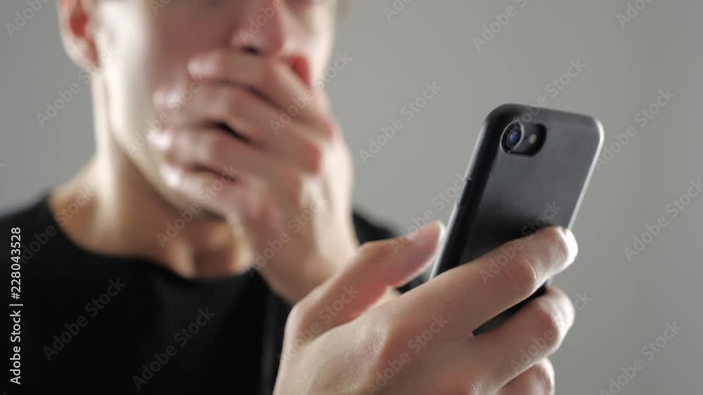 Man unpleasantly surprised and shocked looking into the smartphone. Bad news.