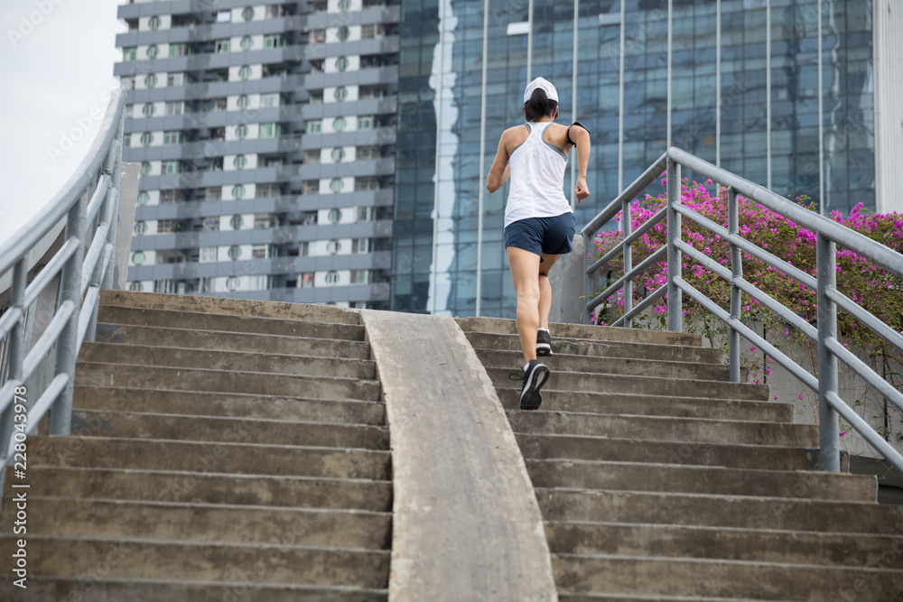 Young woman runner sportswoman running up city stairs