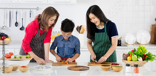 Fényképezés Beautiful Asian woman in red shirt and black  apron teaching her daughter and so
