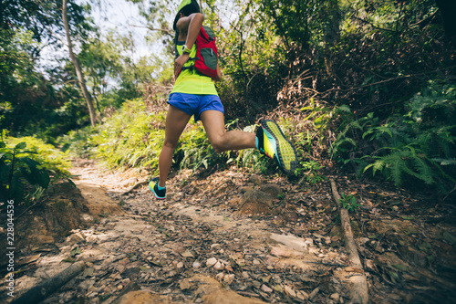 Fotografia Young woman trail runner running on tropical forest trail