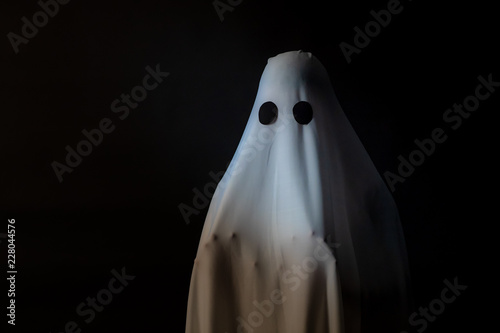 Photography Someone covered with white cloth with big black eyes on black background look like ghost in night