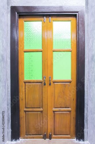 Vintage wooden door with Stained glass on the cement wall