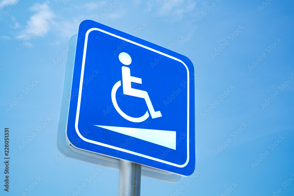 Handicap sign. White symbol over blue background on blue sky background Handicap sign. White symbol over blue background on blue sky background