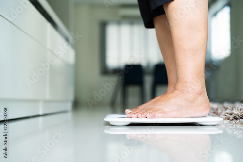 old woman standing on weight scale in living room