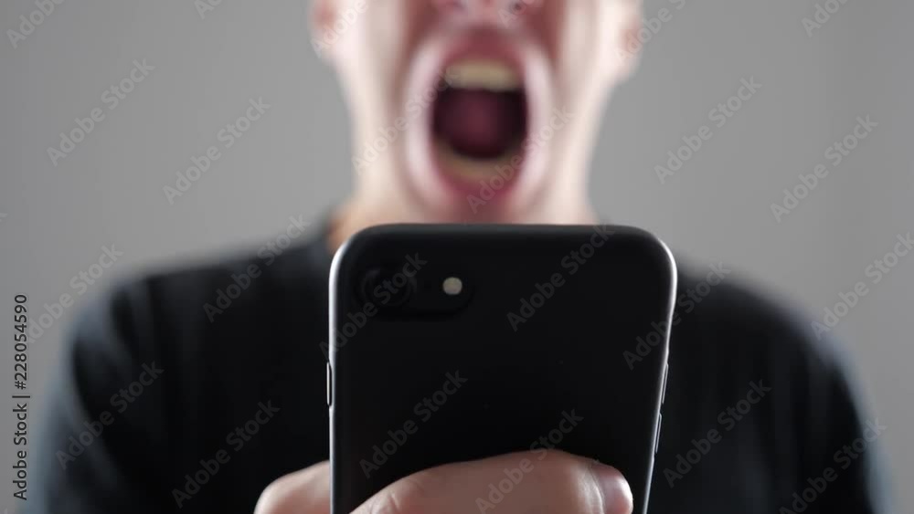 Angry Man Using Smartphone. Furious yelling man with smartphone in hand