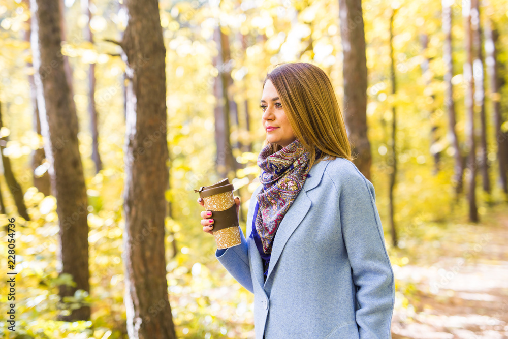 Attractive woman holding a cup of takeaway coffee cup on autumn street Attractive woman holding a cup of takeaway coffee cup on autumn street