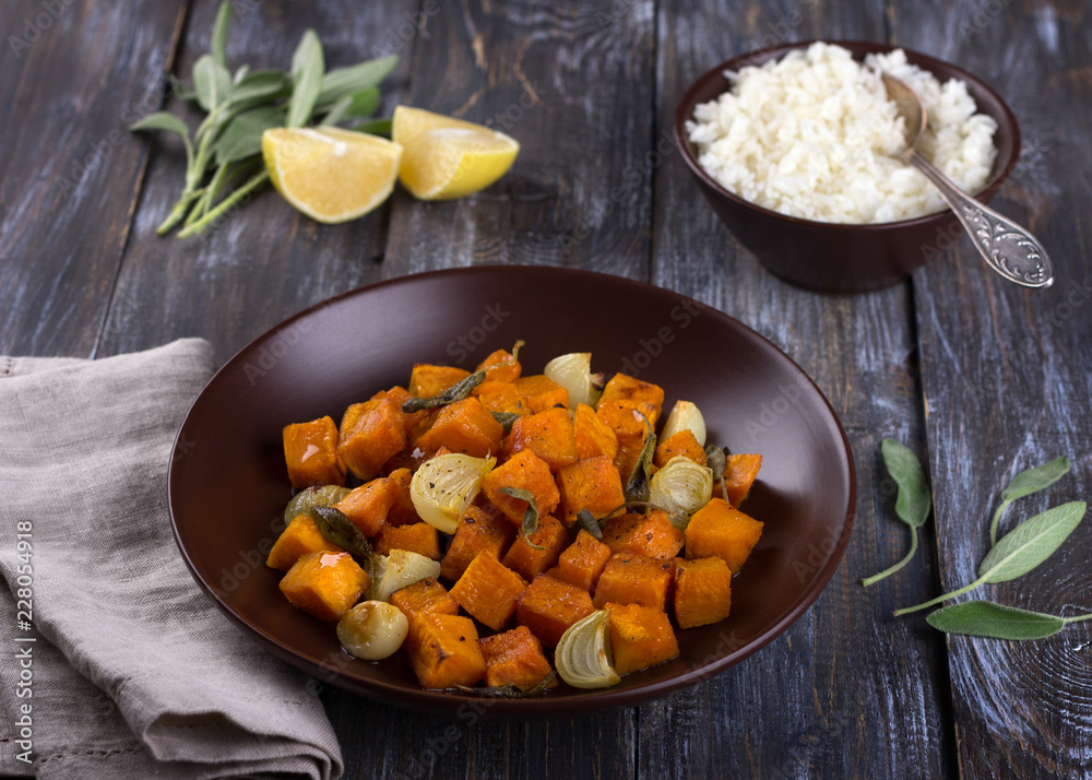 Baked pumpkin with onions, garlic and sage with boiled rice on a wooden table. delicious healthy homemade food Baked pumpkin with onions, garlic and sage with boiled rice on a wooden table. delicious healthy homemade food