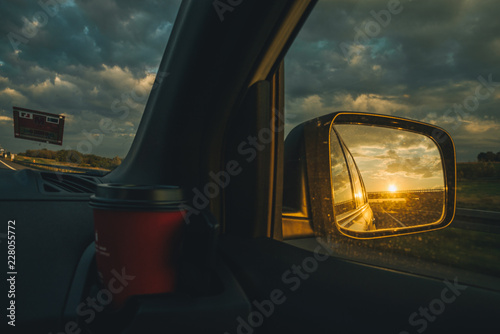 sunset reflection in car mirror on highway