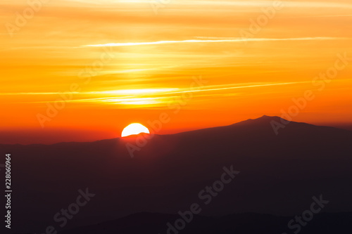 Beautiful sunset with sun coming down behind various layers of mountains