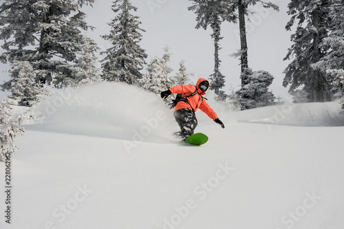 Man running down the mountain slope on the snowboard
