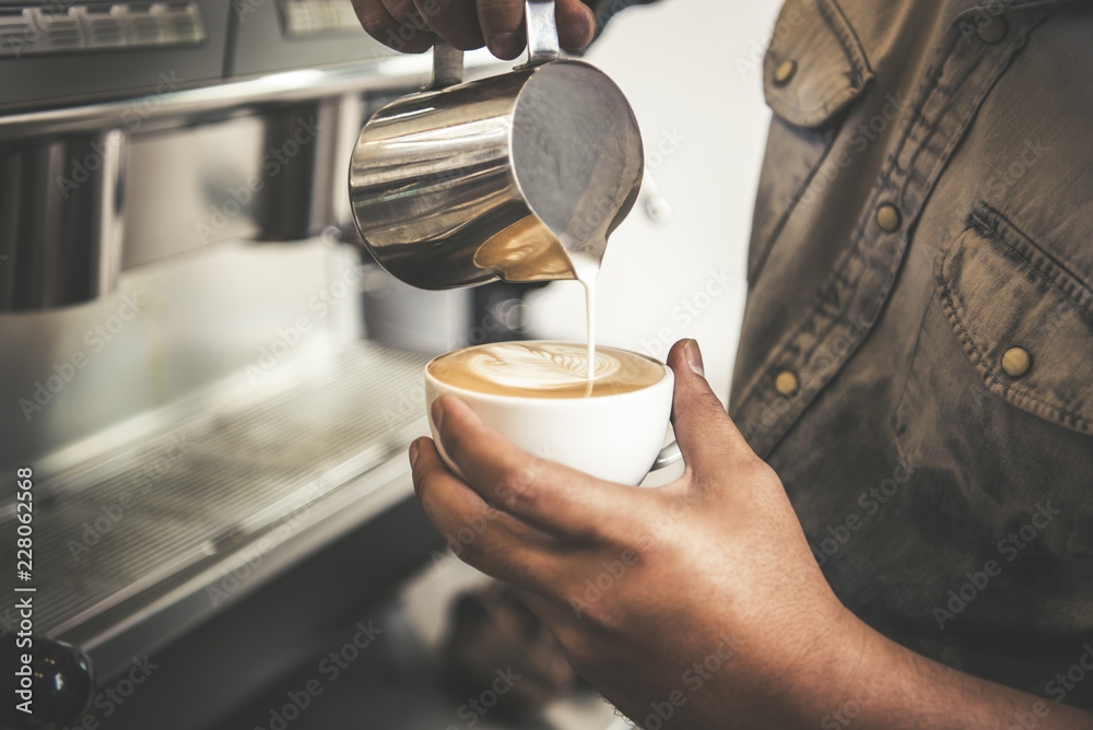 Barista making latte or Cappuccino art with frothy foam, coffee cup in cafe.