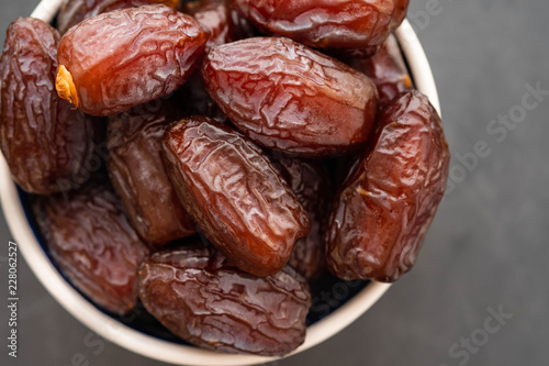 Fresh Medjool Dates in a bowl. Ramadan kareem. Black background. Top view. Copy space.