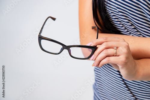 hand of woman holds trendy glasses with black rim on a white background in the studio. Close-up
