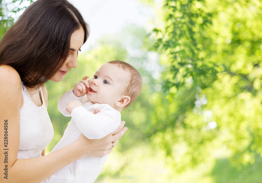 family and motherhood concept - happy smiling young mother with little baby over green natural background family and motherhood concept - happy smiling young mother with little baby over green natural background