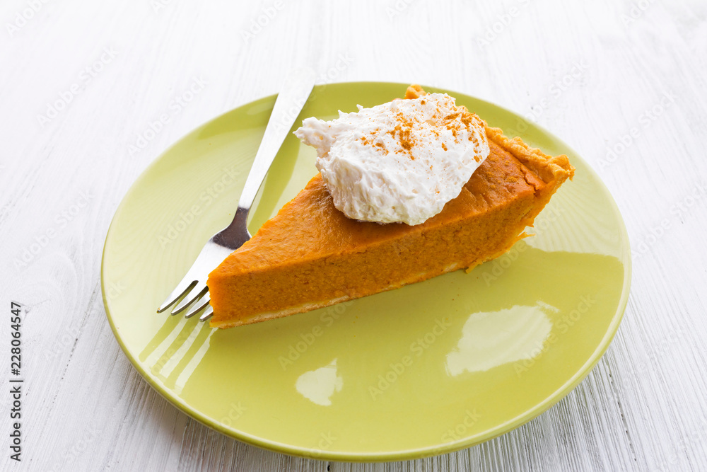 Slice of pumpkin pie with whipped cream over white wooden background Slice of pumpkin pie with whipped cream over white wooden background