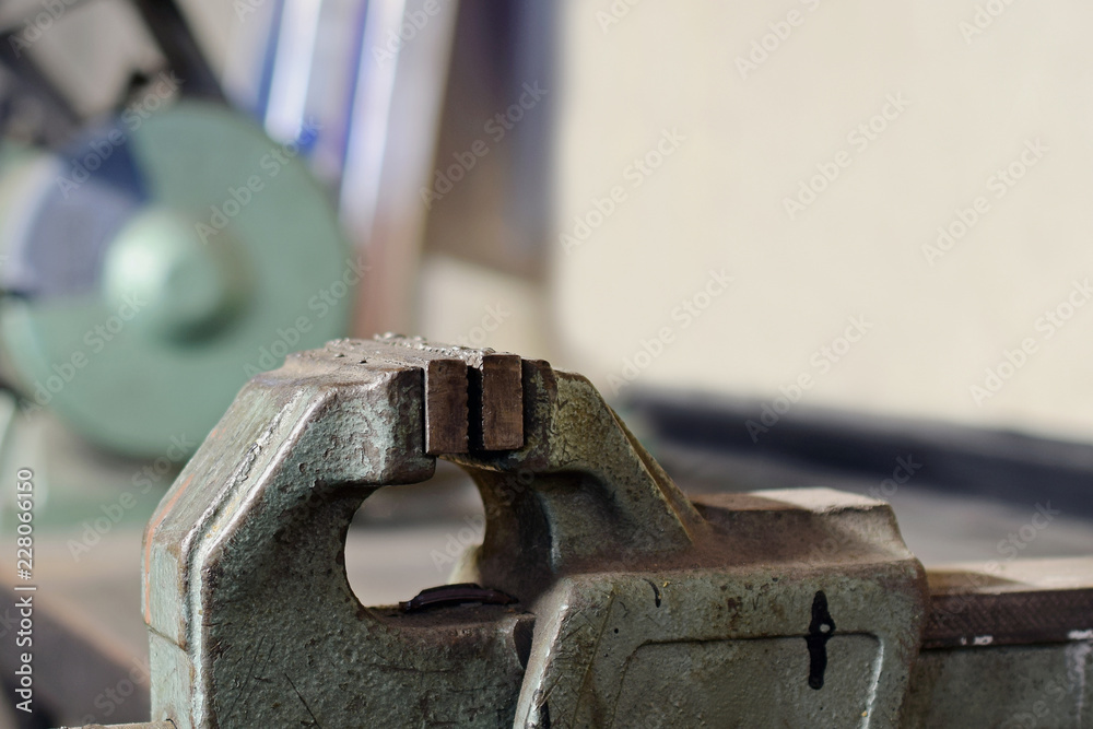 Vise close up on metal workshop. Bench grinder on background. Copy space. Vise close up on metal workshop. Bench grinder on background. Copy space.