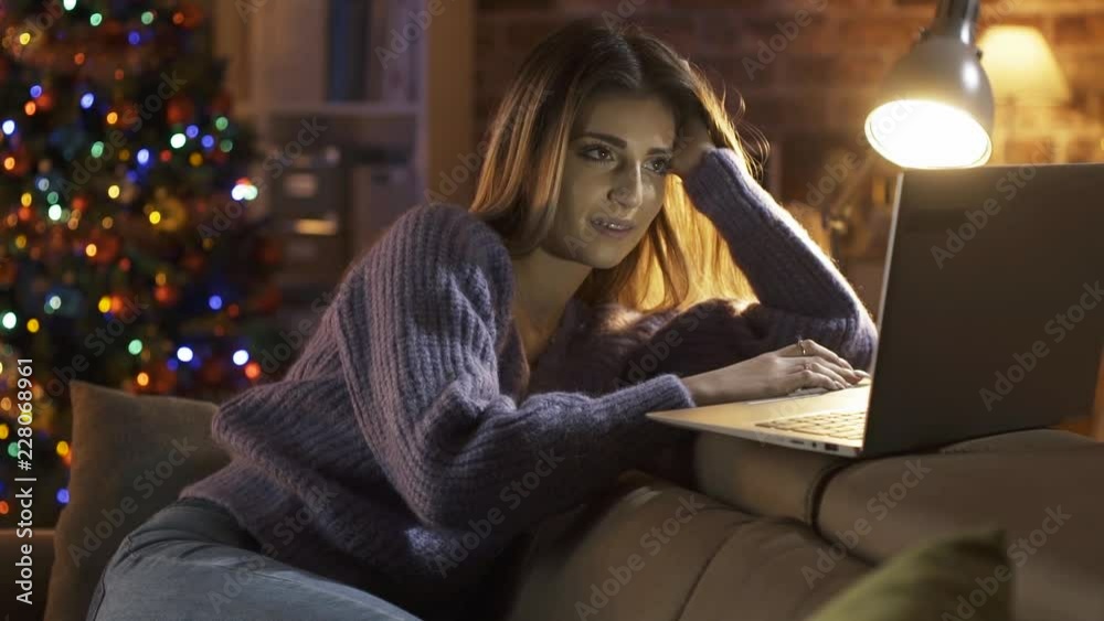 Smiling cute girl chatting online on Christmas Eve Smiling cute girl chatting online on Christmas Eve