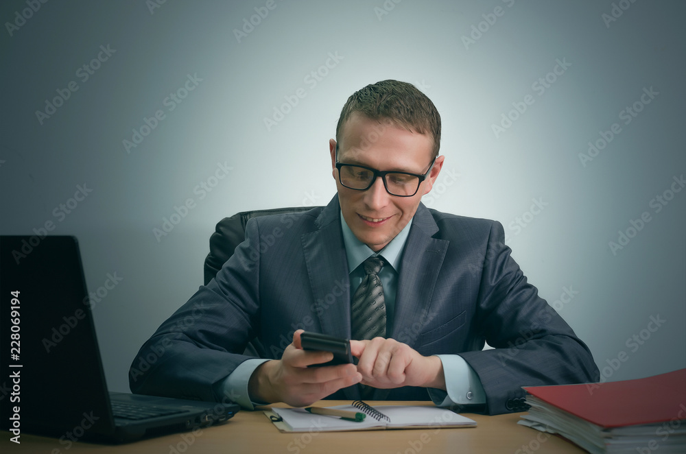 Businessman counts on a calculator and is sitting by the office table. Businessman counts on a calculator and is sitting by the office table.