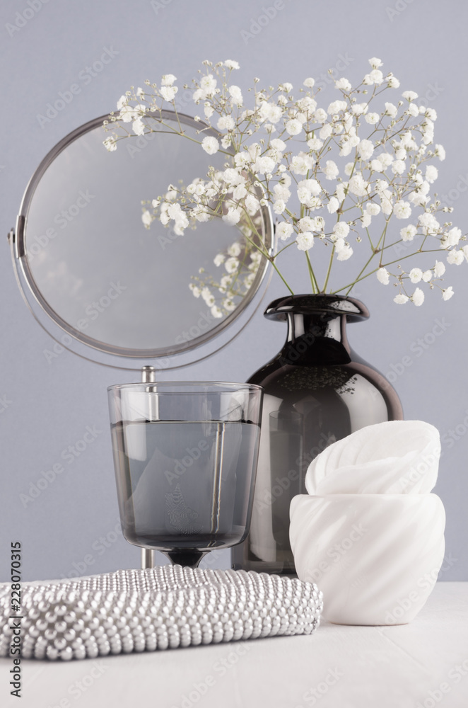 Cosmetic and make up accessories and home decoration black glass vase with  flowers, silver mirror, bowls on soft white wood table and grey wall. Stock  Photo | Adobe Stock