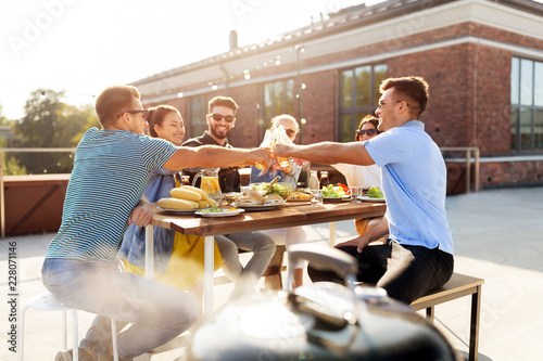 leisure and people concept - happy friends toasting drinks at barbecue party on rooftop in summer photo