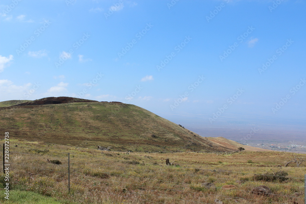 Hawaii landscape: ocean coast, roads to mountain hills, blue sky and small white clouds. Hawaii landscape: ocean coast, roads to mountain hills, blue sky and small white clouds.