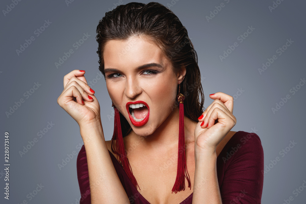 Fototapeta premium Stunning woman with a beautiful makeup wearing long red earrings