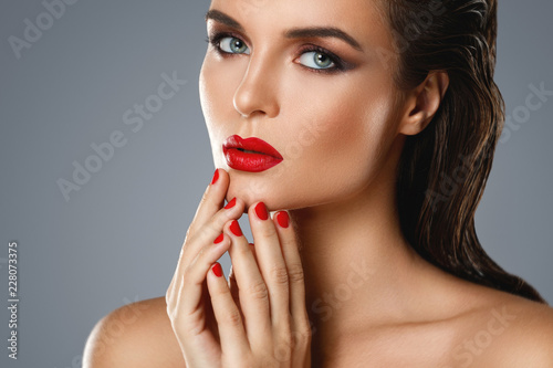 Portrait of beautiful young woman with a red lipstick and nail polish