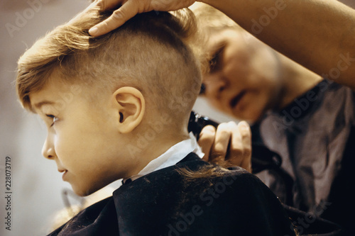 Little boy getting a haircut at barber shop.