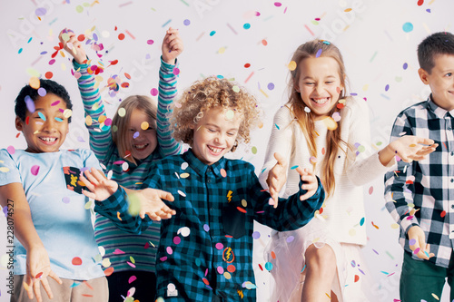 Smiling multicultural group of kids having fun with confetti during friend's birthday