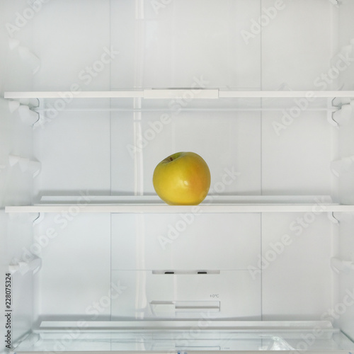 Yellow ripe apple on the shelf in the fridge. Health starvation, lose weight. Raw diet, starving concept.