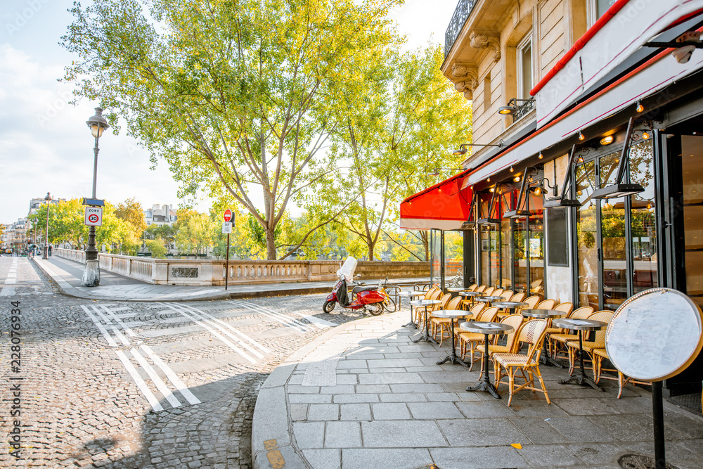 Naklejka premium Widok na ulicę z pięknymi budynkami i tarasem kawiarni o poranku w Paryżu