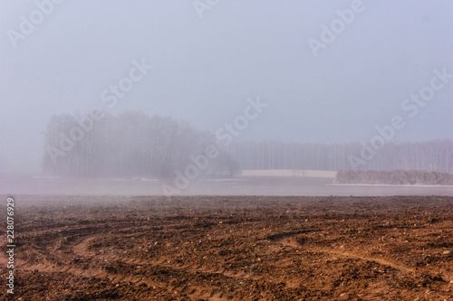 Fog early in the morning over a plowed field.