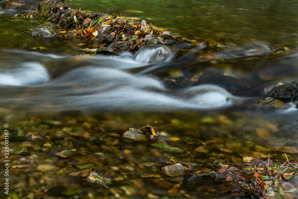 Autumn landscape with mountain river flowing among mossy stones through the colorful forest. Silky smooth stream of clear water. Autumn landscape with mountain river flowing among mossy stones through the colorful forest. Silky smooth stream of clear water.