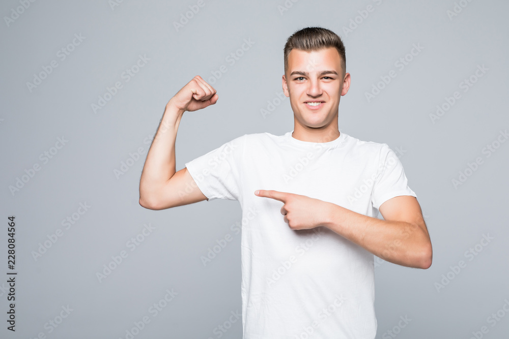 Portrait of a confident young man pointing at his biceps isolated over white background Portrait of a confident young man pointing at his biceps isolated over white background