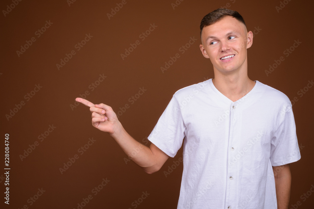 Young man wearing white shirt against brown background Young man wearing white shirt against brown background