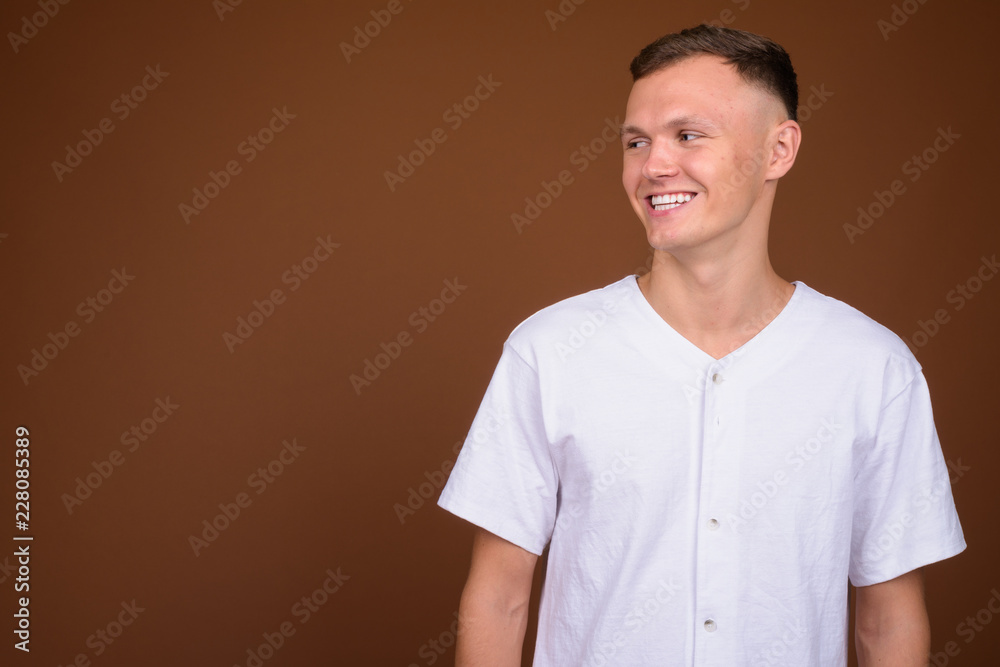 Young man wearing white shirt against brown background Young man wearing white shirt against brown background
