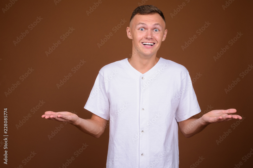 Young man wearing white shirt against brown background Young man wearing white shirt against brown background