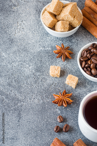 Cup of coffee, brown sugar and cinnamon with anise on concrete background. Copy space